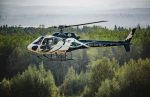 Slave Lake Helicopters' H125 flying over a forest in Alberta, Canada