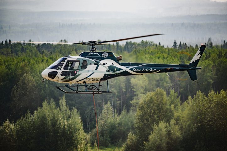 Slave Lake Helicopters' H125 flying over a forest in Alberta, Canada